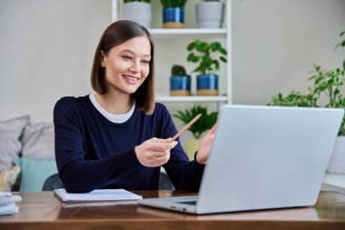 Genç bir üniversite öğrencisi evde oturup sohbet etmek için dizüstü bilgisayarla konuşuyor. İnternet çevrimiçi uzak dersler eğitim eğitimini engelliyor