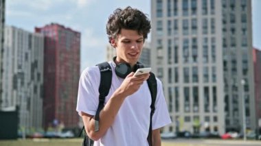 Genç adam akıllı telefondan sesli mesaj kaydediyormuş. Sesli mesaj yolluyormuş. Açık havada telefonla konuşuyormuş. Teknoloji iletişimi yaşam tarzı gençlik kavramı