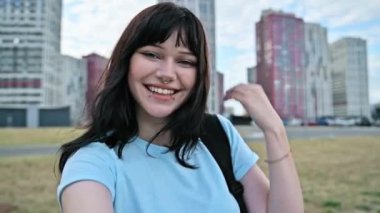 Selfie portresi genç, gülen güzel bir kadın, sırt çantalı mutlu bir üniversite öğrencisi, modern şehir gökdelenleri, yüz piercingli çekici bir kadın, şehir tarzı. Güzellik, gençlik, yaşam tarzı konsepti