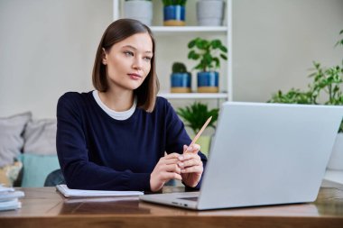 Genç bir üniversite öğrencisi evde oturup sohbet etmek için dizüstü bilgisayarla konuşuyor. İnternet çevrimiçi uzak dersler eğitim eğitimini engelliyor