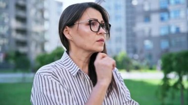 Üzgün, stresli, olgun bir kadın, açık hava portresi. Orta yaşlı ciddi bir kadın, şehir geçmişi var. Depresyon, stres, sorunlar, zorluklar, zihinsel sağlık kavramı