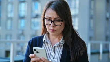 Akıllı telefon kullanan olgun ciddi bir iş kadını, açık ofis binası geçmişi. Daktilo yazan mesajlara odaklanmış zeki kadın. Teknoloji sektörü girişimciliği orta yaşlı insanlar konsepti