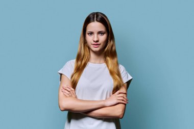 Kızıl saçlı, kendine güveni tam genç bir kız. Mavi stüdyo arka planındaki kameraya bakarak poz veriyor. Başarılı genç kız öğrenci üniversite yaşı gençlik için reklam ürünleri ve hizmetleri