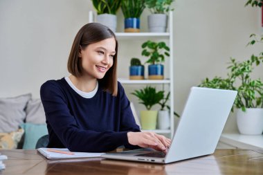 Genç, pozitif bir kadın bilgisayar laptopunu klavyede yazan, çalışan, gülümseyen, mutlu bir genç kadın olarak kullanıyor. Teknoloji, eğitim, eğitim, gençlik kavramı