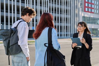 Orta yaşlı iş kadını ajan danışmanı öğretmen sosyal hizmet görevlisi üniversite öğrencileriyle birlikte dijital tablet kullanarak çalışıyor.