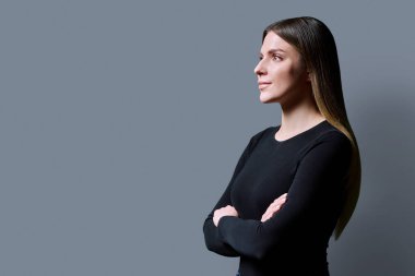 Profil görüntüsü, gri stüdyo arka planında kendine güvenen genç bir kadın, kopyalama alanı. Bayan öğrenci bilgi metninin reklamını yapmak için yer arıyor. Gençlik, eğitim hizmetleri sağlık güzellik işi