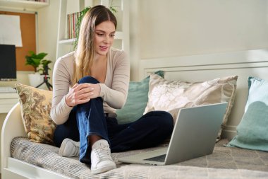 Evde dizüstü bilgisayarı olan genç bir kadın video görüşmesi yapıyor. Sosyal ağlarda iş arkadaşlarıyla sohbet eden bir bayan çevrimiçi olarak bilgisayar başında çalışan serbest çalışan bir öğrenci.