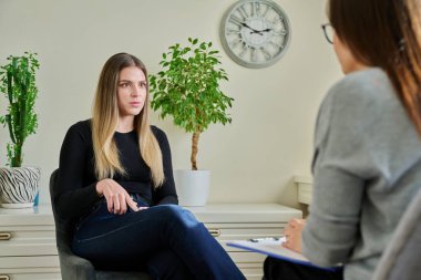 Kadın psikiyatrist psikologla terapi toplantısında gülümseyen genç bir kadın. Psikoloji, psikoterapi, tedavi yardım desteği, gençlik akıl sağlığı konsepti