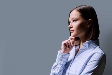 Gri stüdyo geçmişinde genç ciddi iş kadınının profil portresi. Taraf arayan kendine güvenen bir kadın, reklam metni için alanı kopyalayabilir. İş hizmetleri eğitimi güzellik sağlık hizmetleri