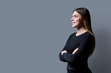 Profil görüntüsü, gri stüdyo arka planında kendine güvenen genç bir kadın, kopyalama alanı. Bayan öğrenci bilgi metninin reklamını yapmak için yer arıyor. Gençlik, eğitim hizmetleri sağlık güzellik işi