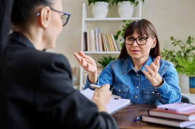 Profesyonel bir terapistle terapide olan orta yaşlı bir kadın hasta. Kadın psikoterapist psikolog, sosyal hizmet görevlisi hastayla konuşuyor. Psikoloji psikoterapi hizmetleri tedaviye yardımcı oluyor