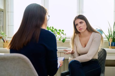 Üzgün, mutsuz, depresyondaki genç bir kadın hasta, kadın psikiyatrist psikologla terapide. Psikoloji, psikoterapi, tedavi yardım desteği, gençlik akıl sağlığı konsepti