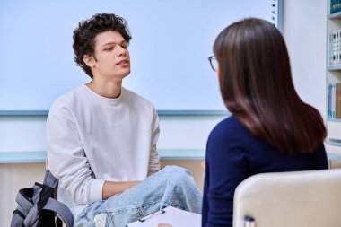 Ofis eğitim binasında genç bir erkek üniversite öğrencisiyle çalışan kadın psikolog. Gençliğin akıl sağlığı, sosyal hizmet, psikoloji, psikoterapi, davranış, destek tedavisi danışmanlığı