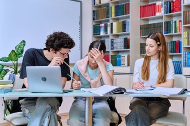 Bir grup lise öğrencisi kütüphane sınıfında okuyor, üç sınıf arkadaşı gülümsüyor, tartışıyorlar, takım çalışması projesi, sınavlara hazırlanıyorlar. Eğitim gençlik iletişimi