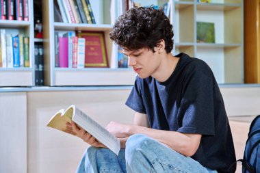 Eğitim binasının içinde kitap okuyan kendine güvenen yakışıklı üniversite öğrencisinin portresi. Eğitim, gençlik, yaşam tarzı kavramı