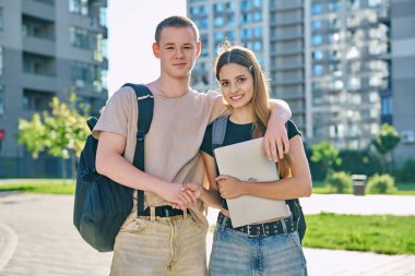 Genç öğrencilerin portresi, erkek ve kız, birlikte açık havada, şehir arka planına bakarak. Gençlik, 17, 18, 19 yaşında, yaşam tarzı, insanlar konsepti