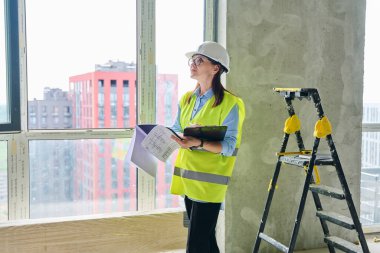 Güvenlik kasklı teknik uzman kadın inşaat işinde çalışıyor. Kendine güvenen endüstriyel kadın mühendis müfettişi müfettiş müteahhit mimarı planlar çizen planlar çizen bir mimar