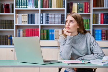 Eğitim kütüphanesinde okuyan genç bir kız öğrenci, gülümseyen bir genç kızın portresi. Eğitim, ergenlik, lise, üniversite, öğrenim, bilgi kavramı