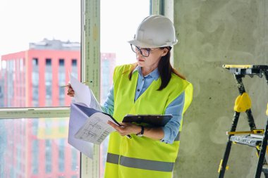 Güvenlik kasklı teknik uzman kadın inşaat işinde çalışıyor. Kendine güvenen endüstriyel kadın mühendis müfettişi müfettiş müteahhit mimarı planlar çizen planlar çizen bir mimar