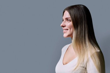 Uzun düz saçlı, güzel, gülümseyen genç bir kadının profil görüntüsü. Moda cilt bakımı saç ürünleri güzellik hizmetleri sağlık konsepti