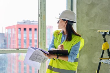 Güvenlik kasklı teknik uzman kadın inşaat işinde çalışıyor. Kendine güvenen endüstriyel kadın mühendis müfettişi müfettiş müteahhit mimarı planlar çizen planlar çizen bir mimar