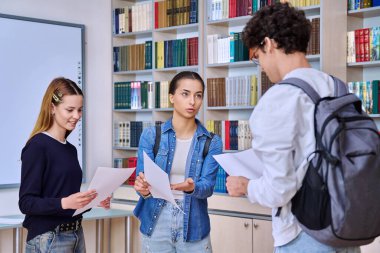 Bir grup üniversite öğrencisi genç kızlar ve kütüphane içinde konuşan bir adam. Eğitim, öğrenim, öğrenim, bilgi, arkadaşlık, gençlik kavramı