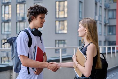 İki arkadaş öğrencisiyle tanışacak. 18-19 yaşlarındaki genç kız ve erkek. Açık havada el sıkışıyorlar. Yaşam tarzı, gençlik, yaşam konsepti