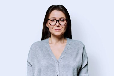 Uzun saçlı, uzun saçlı, gülümseyen esmer kadının portresi beyaz stüdyo arka planında kameraya bakıyor. Orta yaş, yaşam tarzı, güzellik sağlığı, mesleki kariyer kavramı