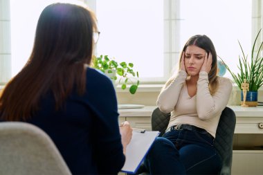 Üzgün, mutsuz, depresyondaki genç bir kadın hasta, kadın psikiyatrist psikologla terapide. Psikoloji, psikoterapi, tedavi yardım desteği, gençlik akıl sağlığı konsepti