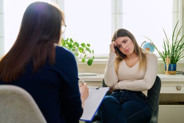 Üzgün, mutsuz, depresyondaki genç bir kadın hasta, kadın psikiyatrist psikologla terapide. Psikoloji, psikoterapi, tedavi yardım desteği, gençlik akıl sağlığı konsepti