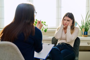 Üzgün, mutsuz, depresyondaki genç bir kadın hasta, kadın psikiyatrist psikologla terapide. Psikoloji, psikoterapi, tedavi yardım desteği, gençlik akıl sağlığı konsepti