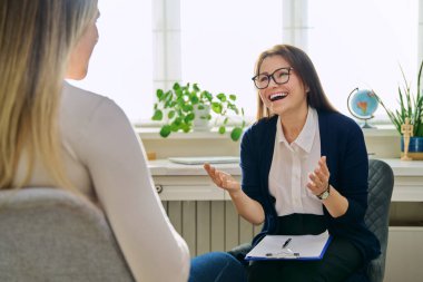 Orta yaşlı kadın psikoterapist genç bir kadınla seans terapisi ruh sağlığı uzmanı sosyal hizmet görevlisi olarak çalışıyor. Not panosuna not alıyor. Psikoterapi psikoloji danışmanlık desteği