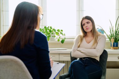Üzgün, mutsuz, depresyondaki genç bir kadın hasta, kadın psikiyatrist psikologla terapide. Psikoloji, psikoterapi, tedavi yardım desteği, gençlik akıl sağlığı konsepti