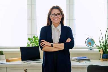 Ofiste kollarını kavuşturmuş kendine güvenen olgun bir kadının portresi. Kameraya bakan başarılı orta yaşlı kadın. İş hayatı yaşam tarzı 40 'lı yılların insan kavramı