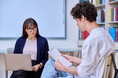 Bayan öğretmen, erkek üniversite öğrencisiyle konuşuyor. Sınıfta akıl hocası ve öğrenci birlikte. Eğitim, eğitim, akıl hocalığı, öğretim, gençlik kavramı