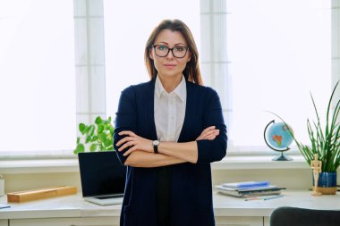 Ofiste kollarını kavuşturmuş, kendine güvenen olgun bir kadının portresi. Kameraya bakan başarılı orta yaşlı kadın. İş hayatı yaşam tarzı 40 'lı yılların insan kavramı