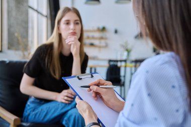 Çalışan ruh sağlığı uzmanı sosyal hizmet görevlisinin elindeki panoya odaklan, genç bir kadınla terapi seansı. Sosyal hizmetler, psikoloji psikoterapi tedavi desteği, akıl sağlığı konsepti