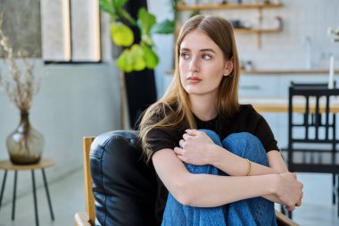 Mutsuz, düşünceli, ciddi bir genç kadın evdeki koltukta oturuyor. Sıkılmış, sıkılmış, genç bir kız. Akıl sağlığı, olumsuz duygular, gençlik kavramı