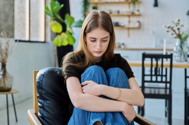 Mutsuz, düşünceli, ciddi bir genç kadın evdeki koltukta oturuyor. Sıkılmış, sıkılmış, genç bir kız. Akıl sağlığı, olumsuz duygular, gençlik kavramı