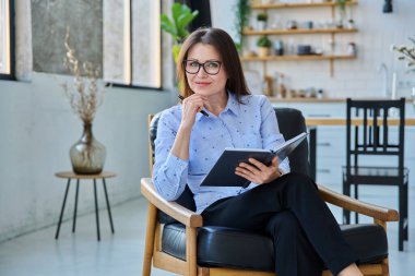 Not defteriyle koltukta oturan kendine güvenen olgun bir iş kadını. Çalışma, hizmet, iş, insan kavramı