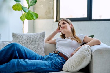 Mutlu, rahat, sakin, güzel, genç bir kadın. Kanepede oturuyor. Elleri başının arkasında. Rahat, rahat, rüya, eğlence, uyum, sakinlik, rahatlama, dinlenme, gençlik, yaşam tarzı konsepti
