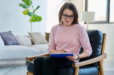 Profesyonel psikolog sosyal hizmet görevlisi kadın portresi ofiste pano ile koltukta oturuyor. Psikoloji, psikoterapi, danışmanlık, tedavi, ruh sağlığı hizmetleri