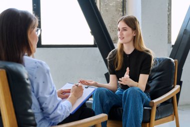 Zihinsel terapi seansında gülümseyen genç bayan hasta uzman psikolog psikoterapist danışman sosyal hizmet görevlisiyle konuşuyor. Hizmet psikolojisi psikoterapi desteği