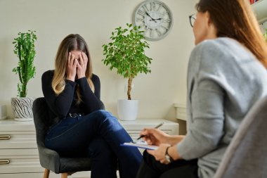 Üzgün, mutsuz, depresyondaki genç bir kadın hasta, kadın psikiyatrist psikologla terapide. Psikoloji, psikoterapi, tedavi yardım desteği, gençlik akıl sağlığı konsepti
