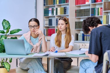 Bir grup öğrenci lise çağında sınıf kütüphanesinde birlikte oturmuş sınavlara hazırlanıyorlar. Eğitim, öğrenme, bilgi, gençlik kavramı