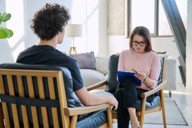 Orta yaşlı kadın psikolog psikoterapist terapist genç erkek hasta ile çalışan zihinsel terapist. Psikoloji psikoterapi sosyal sağlık hizmetleri tedavi destek konsepti