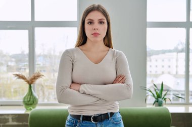 İç mekanda kollarını kavuşturarak poz veren kendinden emin genç bir kadının portresi. Gerçekten güzel 20 'li yaşlarda, sarışın, uzun saçlı, kameraya bakan bir kadın. Güzellik, sağlık, yaşam tarzı, gençlik kavramı