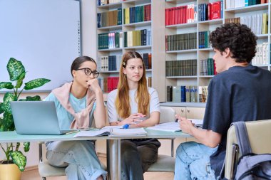 Bir grup öğrenci lise çağında sınıf kütüphanesinde birlikte oturmuş sınavlara hazırlanıyorlar. Eğitim, öğrenme, bilgi, gençlik kavramı