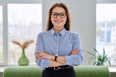 Kollarını kavuşturarak poz veren kendinden emin orta yaşlı iş kadını portresi. Başarılı, profesyonel, olgun kadın psikolog zihinsel terapist danışman yönetici danışman koltukta.