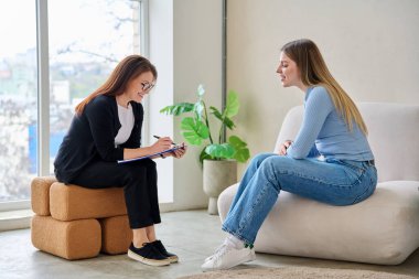 Zihinsel terapi seansında gülümseyen genç bir kadın profesyonel psikolog psikoterapist danışmanıyla konuşuyor. Sosyal hizmetler, tedavi psikoloji psikoterapi sağlığına yardım